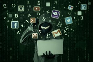 Hacker with laptop and social media icons.