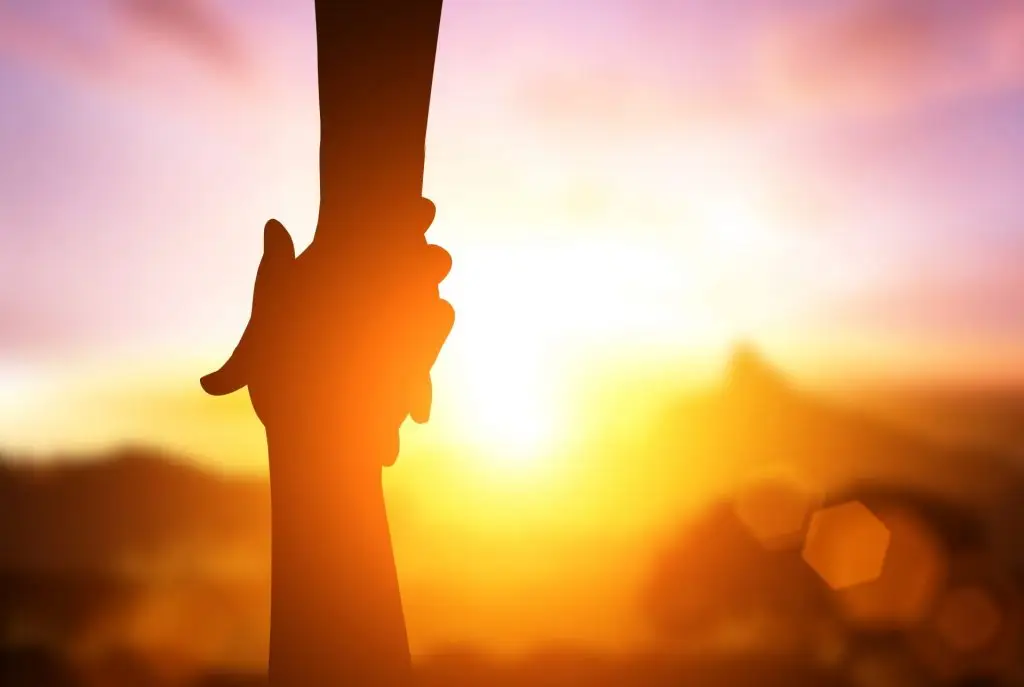 Two hands clasped at sunset